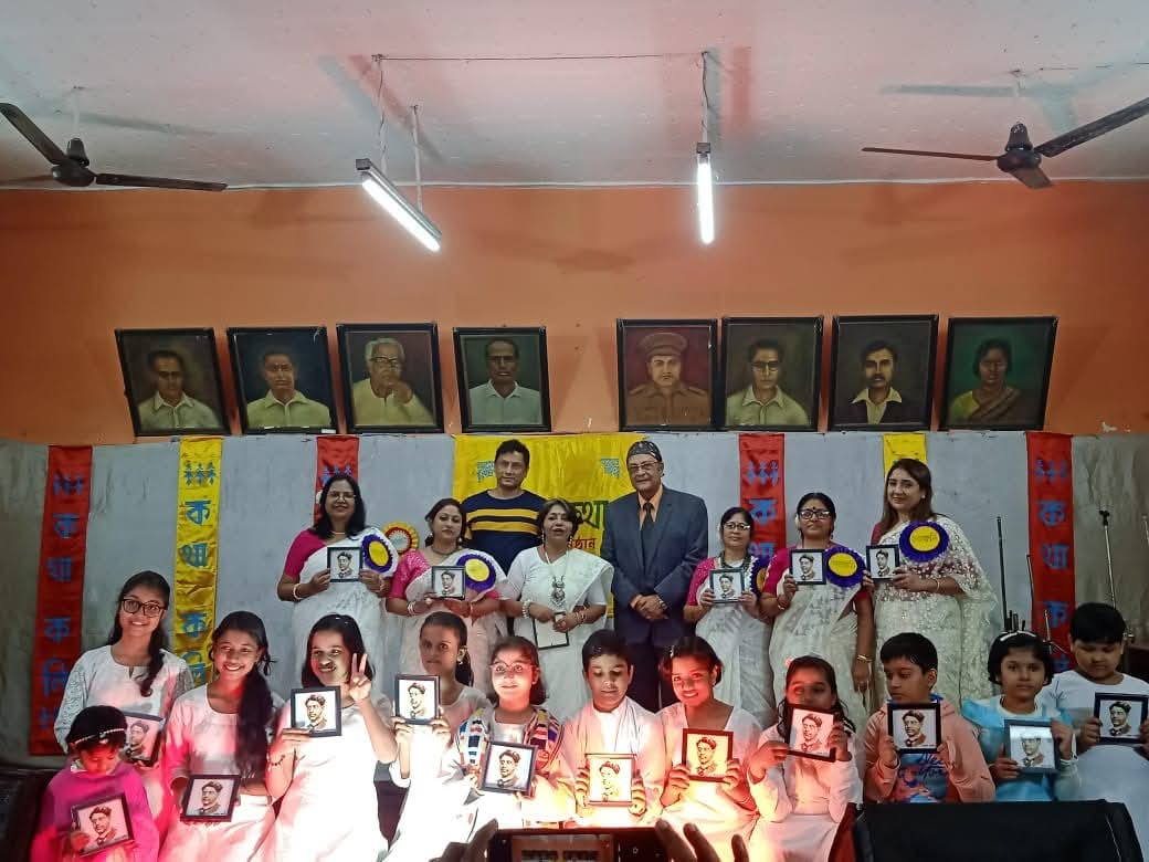 Students and mentor on stage, holding framed portraits of the poets